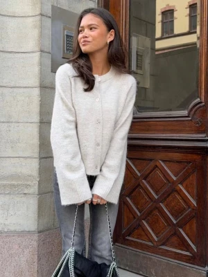 Beige fluffig kofta med knappar Stl 158 /164 - Mysig beige kofta med rund halsringning och knäppning framtill. Koftan har långa ärmar, ribbade muddar och är tillverkad i ett fluffigt, mjukt material som ger en avslappnad look. Använd 2 ggr