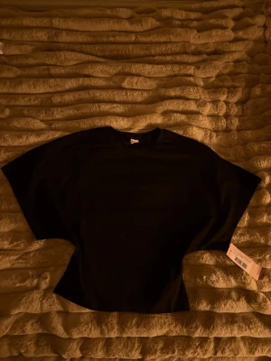 Svart t-shirt med vida ärmar från Nelly - Svart t-shirt från Nelly i storlek S med rund hals och extra vida korta ärmar. Modellen är clean och har en loose passform som ger en chill vibe. Perfekt för dig som gillar minimalistisk stil och vill ha något enkelt men ändå snyggt.