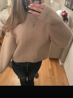 Beige stickad tröja med loose fit - Mysig beige stickad tröja med loose passform och långärmade ärmar. Tröjan har en enkel design utan mönster eller detaljer, perfekt att matcha med jeans eller kjol. Materialet är mjukt och fluffigt, vilket gör den extra skön under kyliga dagar.
