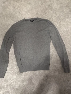 Grå stickad tröja från Matíníque  - Säljer en enkel och stilren grå långärmad tröja från Matíníque. Tröjan har rund halsringning och ribbad nederkant samt ärmar. Perfekt att matcha med jeans eller chinos för en clean look. Tröjan är i storlek S men passar också M. Den är i mycket bra skick. Skriv för flera bilder eller funderingar.