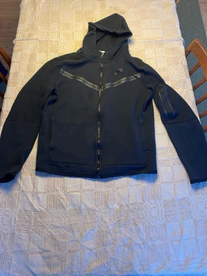 Svart Nike tech hoodie str 158-170 - Svart Nike tech hoodie som är använd några gånger.        Str XL för barn (158-170)