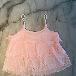 Volanglinne - Säljer ett snyggt rosa volanglinne från Lager 157. Linnet har tunna axelband och är i storlek barn 150 vilket motsvarar ungefär xxs i längden och xs i ”bredden” i damstorlek. Endast använd en gång men har inte kommit till användning sedan dess