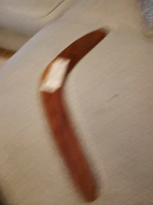 Brun handgjord boomerang från Wungell - Säljer en australiensisk aboriginsk handgjord boomerang från Wungell, 20 tum lång. Boomerangen är brun med målade detaljer i gult, vitt och svart, och har ett coolt motiv på framsidan. Perfekt för dig som vill testa något annorlunda utomhus!