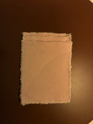 Rosa plånbok i jeansmaterial  - Säljer en handgjord plånbok i ljusrosa jeansmaterial med fransiga kanter. Baksidan har  sugproppar  som gör att den kan fästas på släta ytor, t.ex. mobiltelefonen . Perfekt för kort eller småsaker!