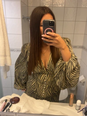  Adoore Zebramönstrad kortklänning - Säljer en superfin  kort klänning från adoore med zebramönster och v-ringning. Endast använd en gång 