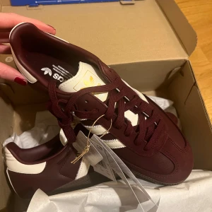 Adidas OG Samba vinröda sneakers - Adidas Samba OG sneakers i vinrött och off white. Aldrig använda. Skorna är köpta på Zalando i slutet av oktober och då köpta som en julklapp. Då Zalandos tider för öppetköp hade justerats så kunde jag tyvärr inte returnera dem pga fel storlek. Kvitto på beställningen finns om så önskas.