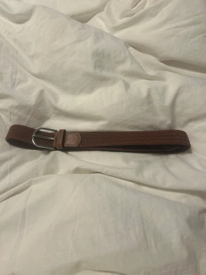 Brunt flätat bälte  - Brunt flätat bälte med silver spänne. Stretchat material 