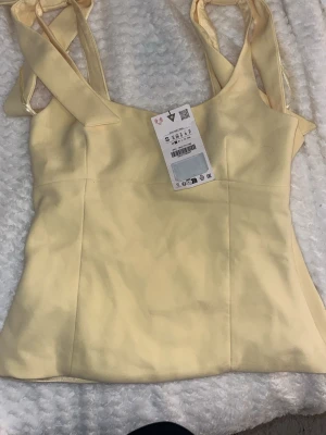 Ljusgul linnetopp med knytband - Trendigt ljusgult linne ifrån Zara. Strl S aldrig använd