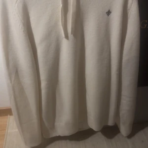 Morris Hoodie vit - Säljer en vit hoodie med snörning i halsen och en liten broderad logga på bröstet. Tröjan har långärmade ribbade muddar och är gjord i ett mjukt material som passar perfekt för kyliga dagar. Enkel och stilren design som funkar till många outfits.