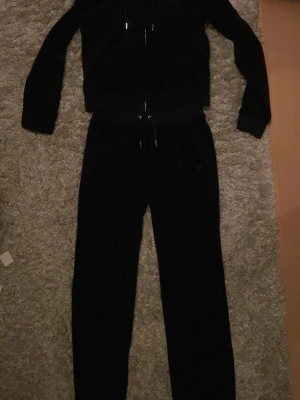 Svarta mjukisbyxor från Juicy Couture - Säljer ett par svarta mjukisbyxor från Juicy Couture i storlek S. Byxorna har en skön, mjuk sammetkänsla och dragsko i midjan med metalländar. Klassisk Juicy Couture-logga broderad på fickan och raka ben. Perfekt för chill dagar.