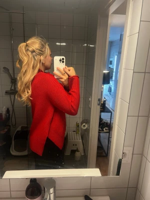 Röd stickad polotröja - Säljer en röd stickad polotröja med lång ärm och snygg strukturstickning. Tröjan har en hög krage och en lite lösare passform med slits i sidorna. Perfekt för kyligare dagar och enkel att styla med jeans eller kjol.