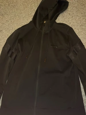 BOSS svart Zip hoodie, storlek M - Svart hoodie med dragkedja från BOSS. Hoodien har diskreta detaljer på ärmarna och bröstet. BOSS bokstäverna på bröstet har lossnat lite annars i gott skick.