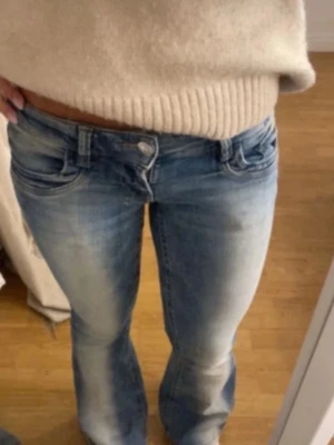 Blå bootcut jeans låg midja gina 14+ - Säljer ett par blå jeans med snygg bootcut och låg midja. Jeansen har klassisk femficksdesign och är tillverkade i ett mjukt jeansmaterial med lätt tvättad look. Perfekta för dig som gillar en avslappnad och trendig stil.
