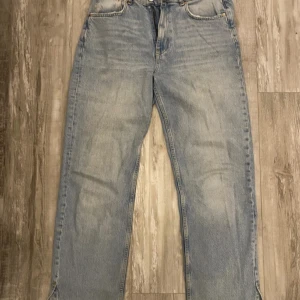 Ljusblå wide jeans från Gina Tricot - Säljer ett par ljusblå jeans från Gina Tricot Premium Denim med breda ben och slits vid benslutet. Jeansen har klassisk femficksdesign och är tillverkade i jeansmaterial. Perfekt för dig som gillar en loose och avslappnad stil.