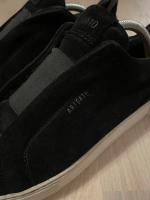 Axel Arigato 360 Laceless sneakers - Snygga skor i svart mocka och vit sula från Axel Arigato i storlek 42. Nypris 2500kr - utgången modell, går alltså går ej att få tag på längre! Skorna har några små defekter här och där men inget som påverkar skorna mycket alls! (Se bilder) OBS!! Ingen innersula ingår vid köp av skorna-därav lägre pris. Hör av er vid frågor!🔥🤝