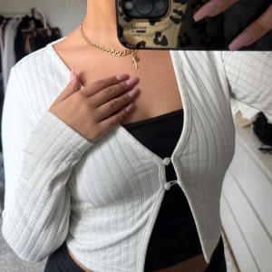 Vit ribbad kofta - Säljer en stilren vit ribbad kofta med lång ärm och knappar framtill. Perfekt för lager-på-lager och att matcha med olika toppar. Koftan är croppad och ger en modern look.