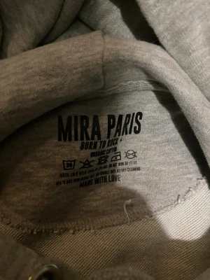 Grå hoodie med röd text från Mira Paris - Grå hoodie från Mira Paris i ekologisk bomull, storlek S. Sitter som en XS. Använd 1-3gg max, ny pris 1700kr