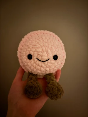 Virkad jellycat macaron - Söt handgjord virkad leksak med mjuk, fluffig textur. Ljusrosa kropp, bruna ben och svarta ögon. Perfekt som present eller dekoration. 🥰