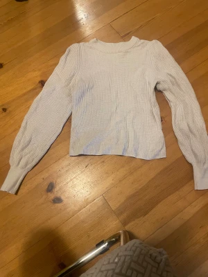 Vit ribbad stickad tröja från Cubus - Säljer en vit stickad tröja från Cubus i storlek S. Tröjan har ribbad struktur, rund hals och långa ärmar med breda muddar. Perfekt för dig som gillar enkel och clean stil med lite volym i ärmarna.