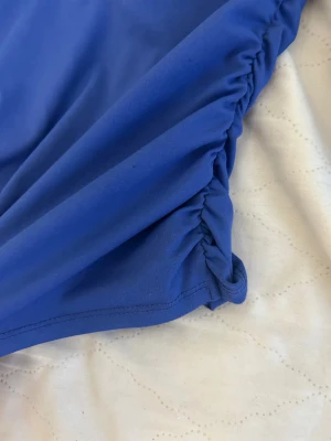 Blå långärmad topp från SHEIN XS - Säljer en blå långärmad topp från SHEIN i storlek XS. Toppen har en fyrkantig urringning och snygga rynkade detaljer på sidorna som ger en cool form. Materialet är mjukt och stretchigt, perfekt för dig som gillar en slim passform.