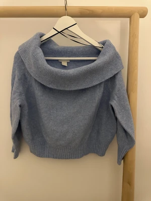 H&M Ljusblå stickad tröja OFF-THE-SHOULDER - Ljusblå stickad off-the-shoulder tröja från H&M i storlek S. Tröjan har ribbade detaljer.