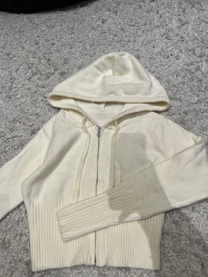 Vit ribbad hoodie från Musera XS/S - Säljer en vit hoodie från Musera i storlek XS/S. Tröjan har ribbade muddar och nederkant, dragkedja framtill och en skön huva. Materialet är mjukt och består av 89% akryl och 11% polyamid. Perfekt för chill dagar och snygg till jeans.