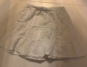 Vit volangkjol från New Yorker - En supersöt vit kortkjol från new yorker i storlek XS. Kjolen har broderade spetsdetaljer med resår i midjan för bra passform💗💗