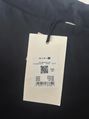 Svart linnetopp NW Movement XL - Svart linnetopp från NW Movement i storlek XL. Toppen har breda axelband och en rak, croppad passform som ger en clean och modern look. Materialet är mjukt och följsamt, perfekt för att styla med jeans eller kjol. Snygg och enkel att matcha med allt.