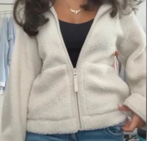 Vit teddyjacka hm - Mysig vit teddyjacka med fluffig yta och hel dragkedja framtill. Jackan har två stora fickor och en hög krage som ger extra värme. Perfekt för att hålla sig varm och se chill ut under kyliga dagar. Passar till jeans och sneakers för en avslappnad vibe.