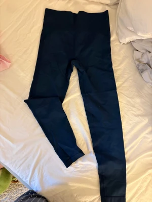 Mörkblå seamless leggings - Mörkblå seamless leggings med hög midja och scrunch-detalj bak. Tight passform och stretchigt material som sitter skönt på kroppen. Perfekta för gymmet eller chill hemma. Snygg och enkel design utan synliga loggor.