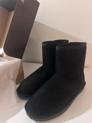 Svarta boots från B&W - Svarta boots från B&W med mjuk insida och mockaliknande utsida. Skorna har rund tå, platt sula och är vattenavvisande. Perfekta för kyliga dagar och har en klassisk, enkel design med diskret logga bak på hälen. Skorna är nya.❄️🩷