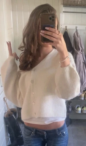 Vit kofta med knappar och ballongärmar - Säljer en fluffig vit kofta med v-ringning och pärlemorknappar. Koftan har ballongärmar och ribbade muddar vid ärmslut och nederkant. Perfekt att slänga på sig när det är lite kyligt ute. Supermjuk och skön att bära.💞💞