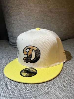 D Keps Gul & Vit - Gul & Vitt keps med D som logga. Strl 55,8