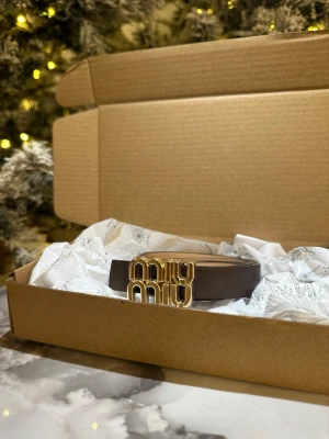 Brun skinnväst från Miu Miu - Supersnygg brun väst från Miu Miu med exklusiv känsla. Västen har ett stilrent utseende och är gjord i skinn med ett coolt guldspänne framtill där Miu Miu-loggan syns tydligt. Perfekt för att lyfta din outfit med en lyxig touch.