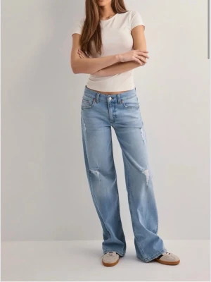 Wide ljusblå jeans med slitningar - Säljer ett par ljusblå jeans med breda ben och coola slitningar på framsidan. Jeansen har klassisk femficksdesign, medel midja och är tillverkade i mjukt denim. Perfekta för dig som gillar avslappnad och trendig stil.
