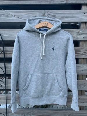 Grå Ralph Lauren Hoodie  - Mycket snygg Grå Ralph Lauren Hoodie. Storlek S, kan även passa en större XS. Mycket fint skick, nästan nyskick. Enbart använd ett fåtal gånger. Hör gärna av er vid funderingar🙌 Perfekt för vinterkylan☃️🧤