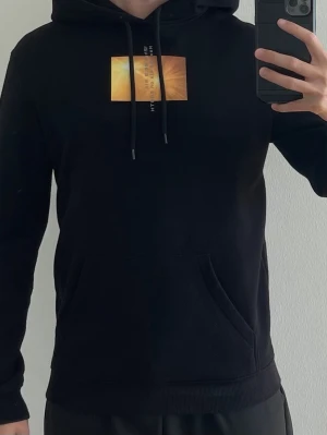 Hoodie - Svart hoodie med tryck fram och bak. Storlek XS.