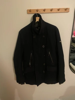 Svart rock från Hackett, storlek L - Fodrad vinterjacka från Hackett London i storlek L. Jackan är i bra skick och är perfekt för vintern. Passar dig som är ungefär 180-190 cm lång. 