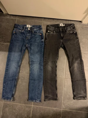 Två par skinny jeans från 157 - Två par jeans från 157, ett par i klassisk blå tvätt och ett par i mörkgrå. Båda har fem fickor, smal passform och normal midja.