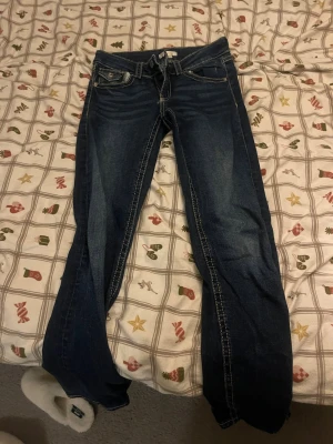 Mörkblå bootcut jeans med kontrastsömmar - Snygga mörkblå jeans med bootcut passform och tydliga kontrastsömmar längs benen. Klassisk femficksdesign och låg midja. Jeansen är från Gina Young och superfina, säljer då det inte passar mig längre