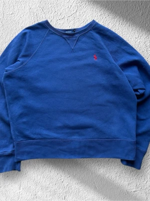 Blå Ralph Lauren Tröja - Klassisk Ralph Lauren tröja i blå färg. Tröjan är i bra skick men har tyvärr en hyfsat stor fläck och ett jätte litet hål. (Se sista bilderna) |  Storlek: XS | Skick: Bra skick! Ett litet hål och en  fläck vid  nacken.   | Borde gå att få bort fläcken men vet inte säkert! (Se sista bilden) | Färg: Blå | Märke: Ralph Lauren | Modell: Sweatshirt, tröja   |  Hör gärna av dig vid frågor så svarar jag så fort jag kan! 😁| 