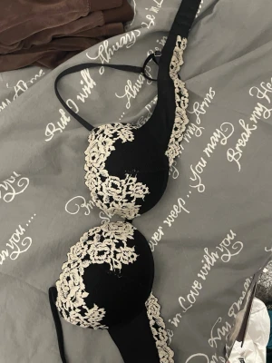 Svart spets-bh från Intimissimi - Säljer en svart bh från Intimissimi med snygga vit spetsdetaljer i blommönster. Bh:n har vadderade kupor och tunna axelband, ingen push upp. Perfekt för dig som gillar en elegant och feminin look. Den e som ny och använt få gånger 💕