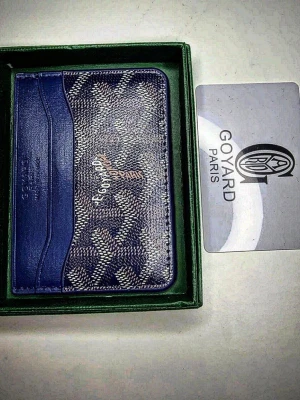 Blå mönstrad plånbok - Säljer en snygg blå plånbok med ikoniskt mönster och flera kortfack. Plånboken har en stilren design och är tillverkad i skinn med detaljer i blått och vitt. Perfekt för dig som vill ha något exklusivt och trendigt i fickan.