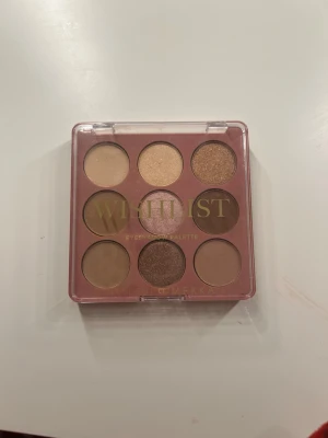 Wishlist ögonskuggspalett Makeup Mekka - Säljer en Wishlist ögonskuggspalett från Makeup Mekka med 9 nyanser i varma bruna, beige och guldiga toner. Paletten har både matta och skimriga skuggor, perfekta för att skapa olika looks. Kommer i en smidig plastförpackning med genomskinligt lock.