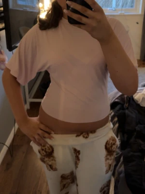 Ljusrosa croppad t-shirt - Säljer en ljusrosa croppad t-shirt med korta ärmar och rund hals. Toppen har en enkel och stilren design, perfekt att matcha med jeans eller kjol. Materialet känns mjukt och lätt mot huden.