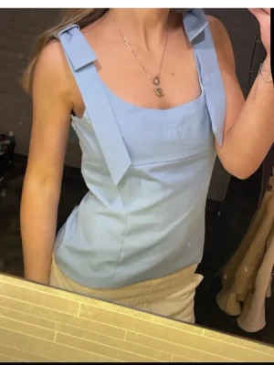 Ljusblå linnetopp med rosetter - Supersöt ljusblå linnetopp med breda axelband som knyts i rosetter🩵🩵storleken är xs men är mer som en S elr M och passar någon med större byst