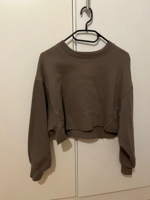Croppad sweatshirt mörkgrå - En mörkgrå croppad sweatshirt med lite puffigare ärmar. Tröjan är i storlek S och är köpt från PULL&BEAR  Är i väldigt fint skick utan synlig användning. 