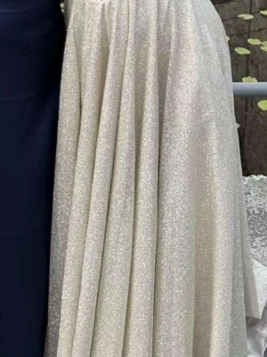 Glittrig champagnefärgad långklänning - Säljer en magisk långklänning i champagnefärg med glittrigt tyg och vacker slits framtill. Klänningen har en axelbandslös design och ett svepande fall som ger en riktigt elegant look. Perfekt för bal eller fest! Knytning i ryggen för justerbar passform.