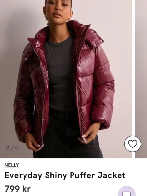 Vinröd jacka från Nelly - Säljer den populära glansiga vinröda pufferjackan från Nelly med huva och dragkedja. Andvänd fåtal gånger bra skick och väldigt varm. Jackan är vadderad och har en riktigt snygg, modern look med quiltade partier. Perfekt för kalla dagar när du vill sticka ut lite extra.