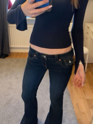 Mörk blå långärmad croppad topp - Säljer en mörkblå , croppad långärmad topp med rund halsringning och slits vid ärmsluten. Toppen har en slim passform och är gjord i mjukt, stretchigt material som sitter snyggt mot kroppen. Perfekt att styla med jeans eller kjol.